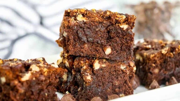 Brownies with nuts and caramel stacked on a plate.