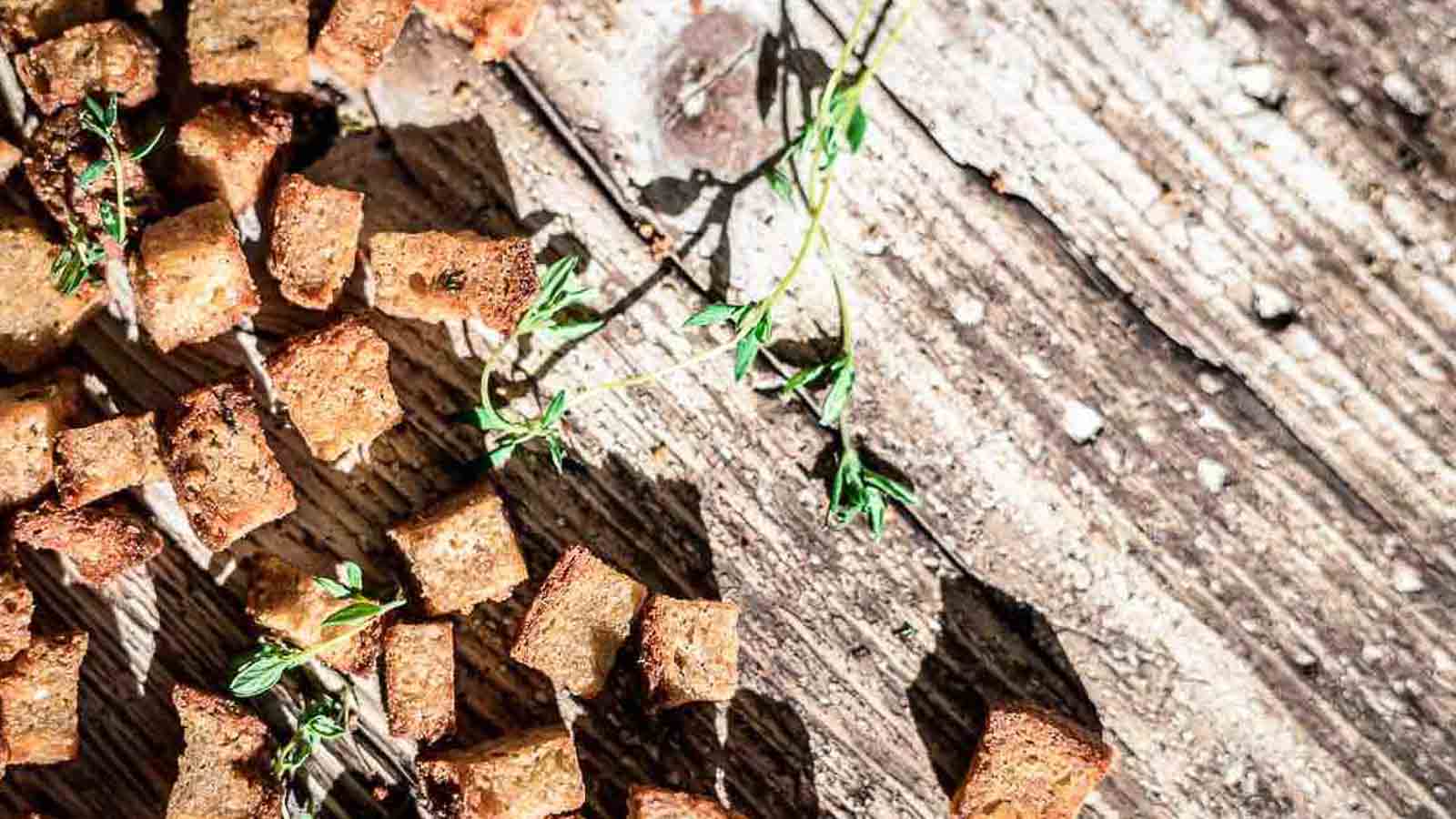 Low angle shot of croutons on a small metal baking sheet.