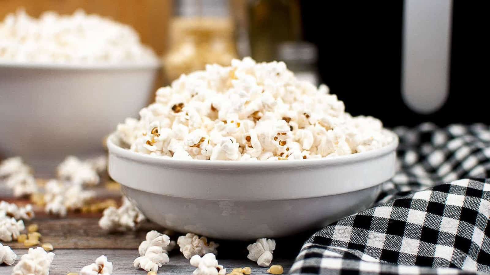 Popcorn in a white bowl with a black and white checked napkin.