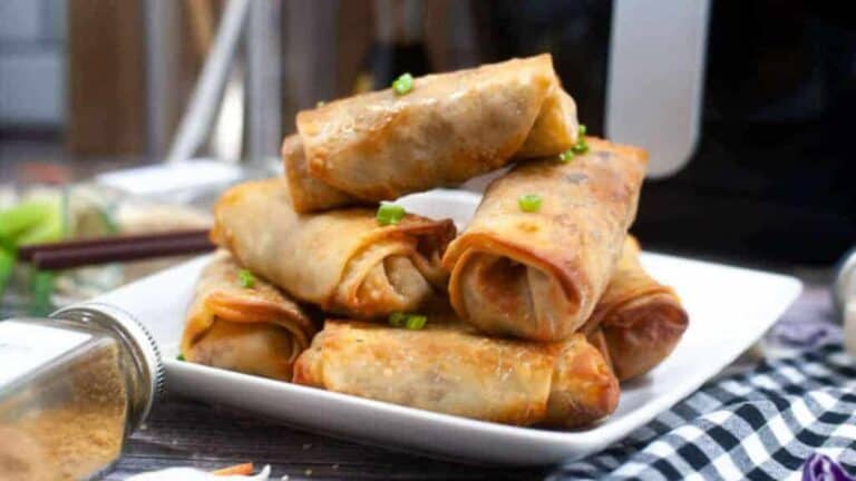 Stacked spring rolls on a white plate.