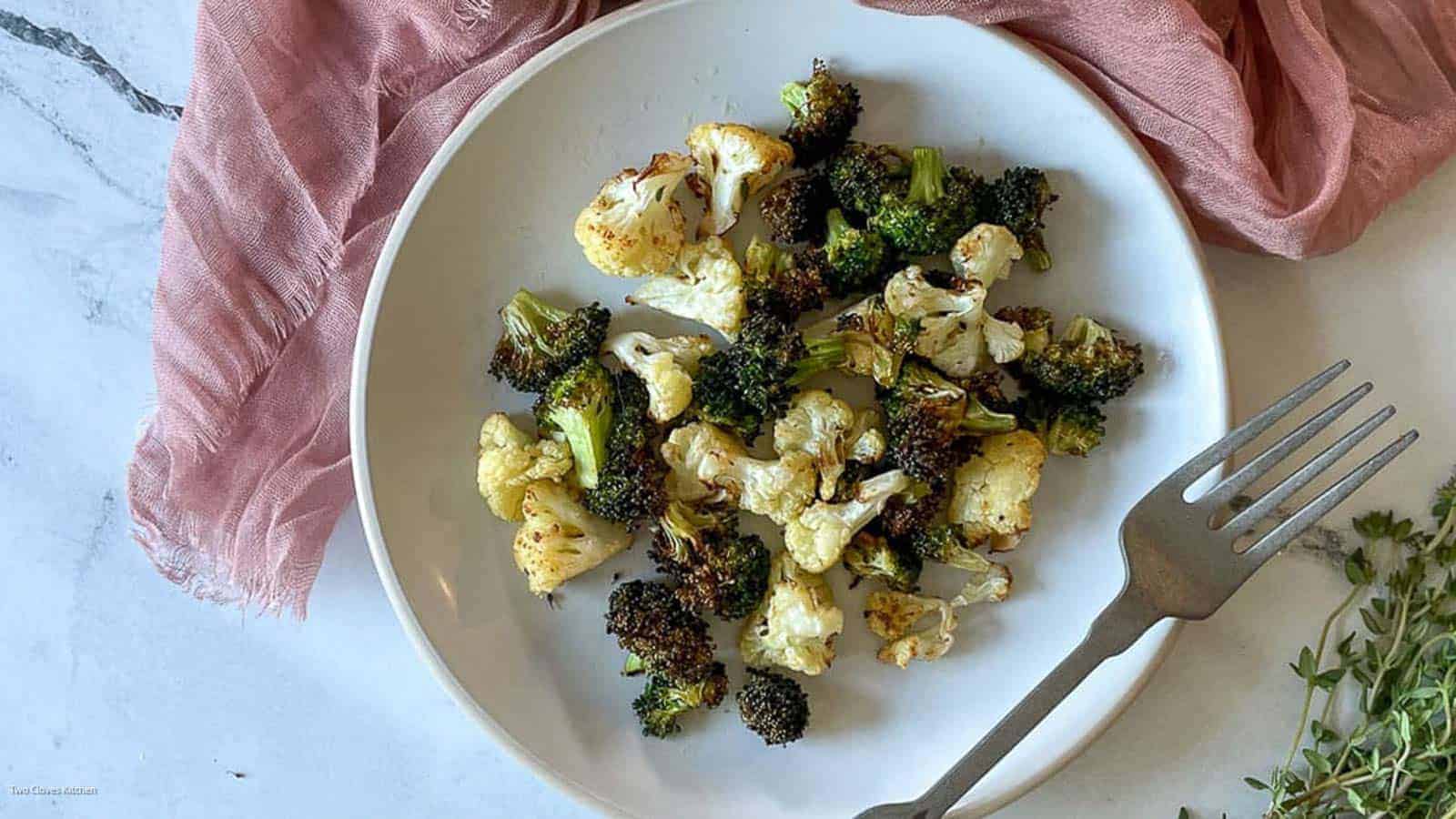 Air fried broccolini on a plate with lemons in the background.