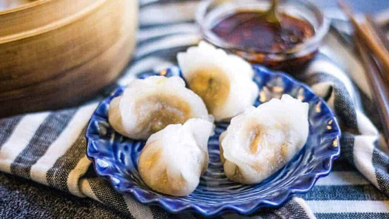 Low angle shot of dumplings with a steamer basket in the background.