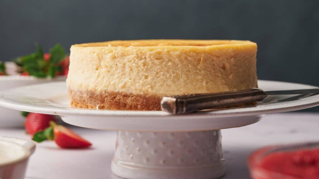 A slice of cheesecake on a white plate with strawberries.