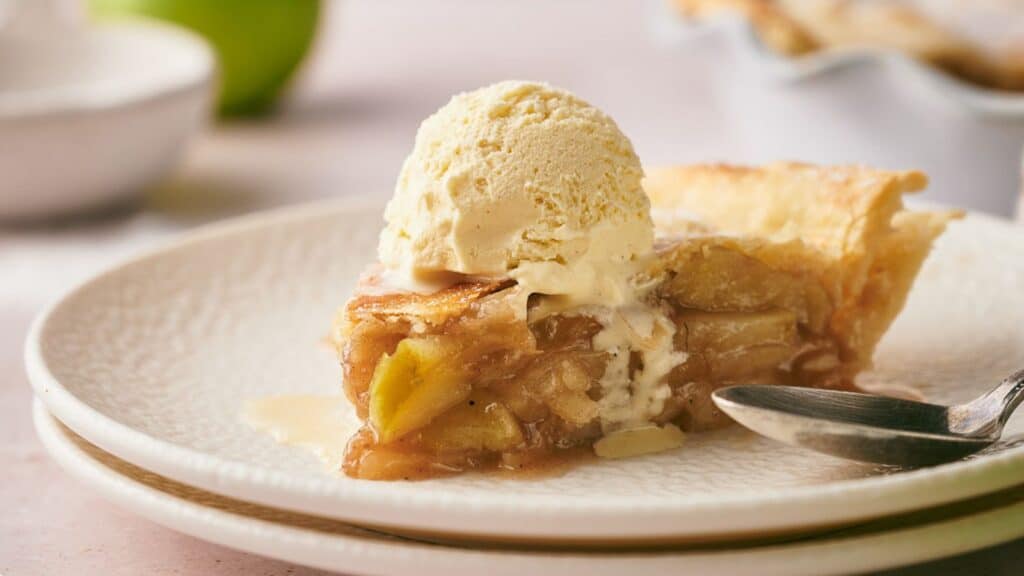 A slice of apple pie with ice cream on a plate.