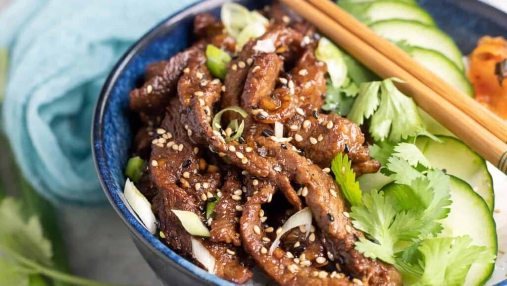 A blue bowl filled with asian beef and vegetables.