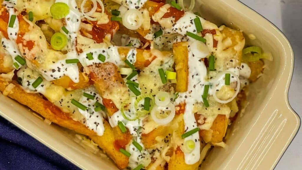 A baking dish filled with french fries and sour cream.