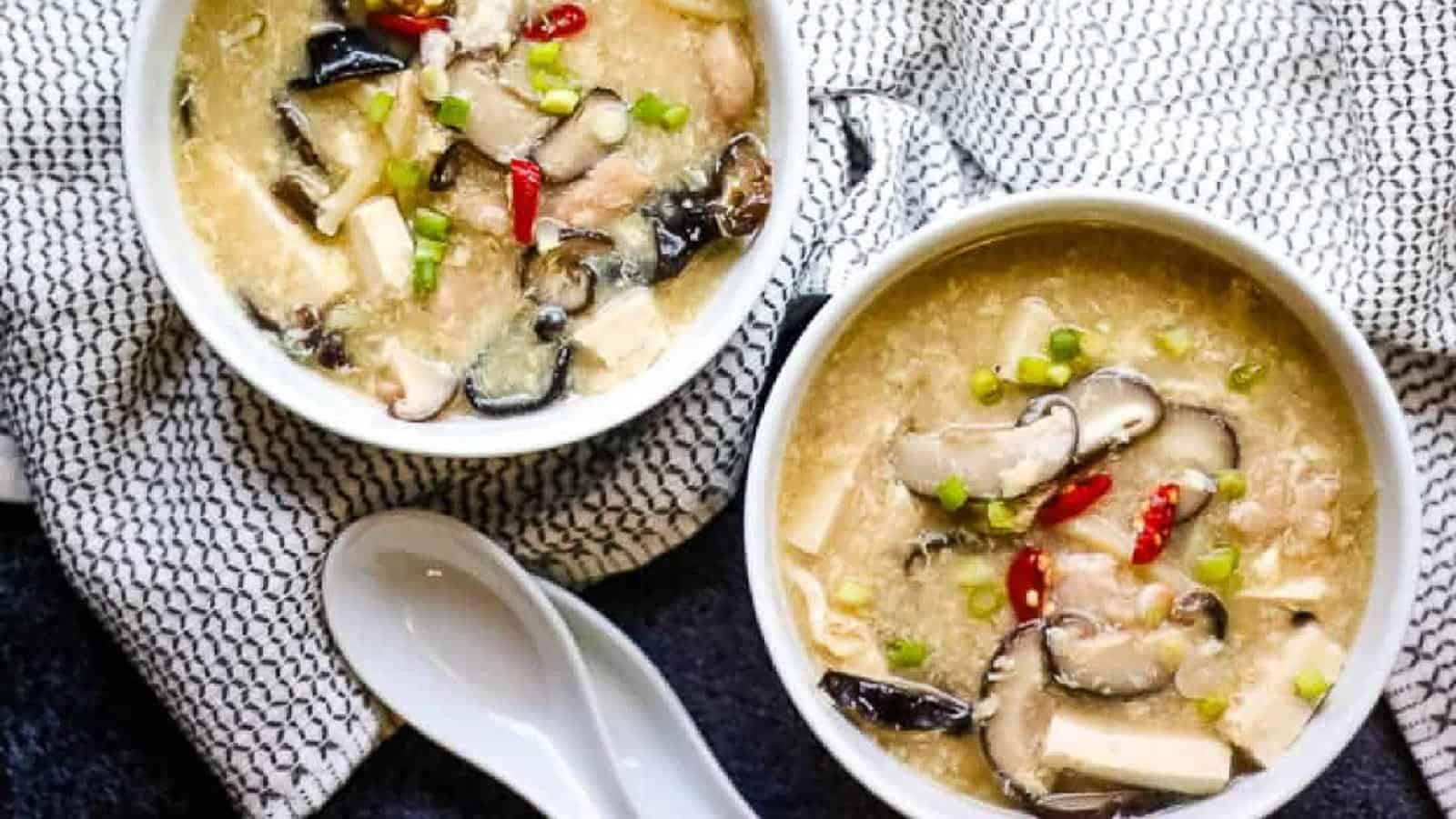 Overhead shot of two white bowls with chicken hot and sour soup.