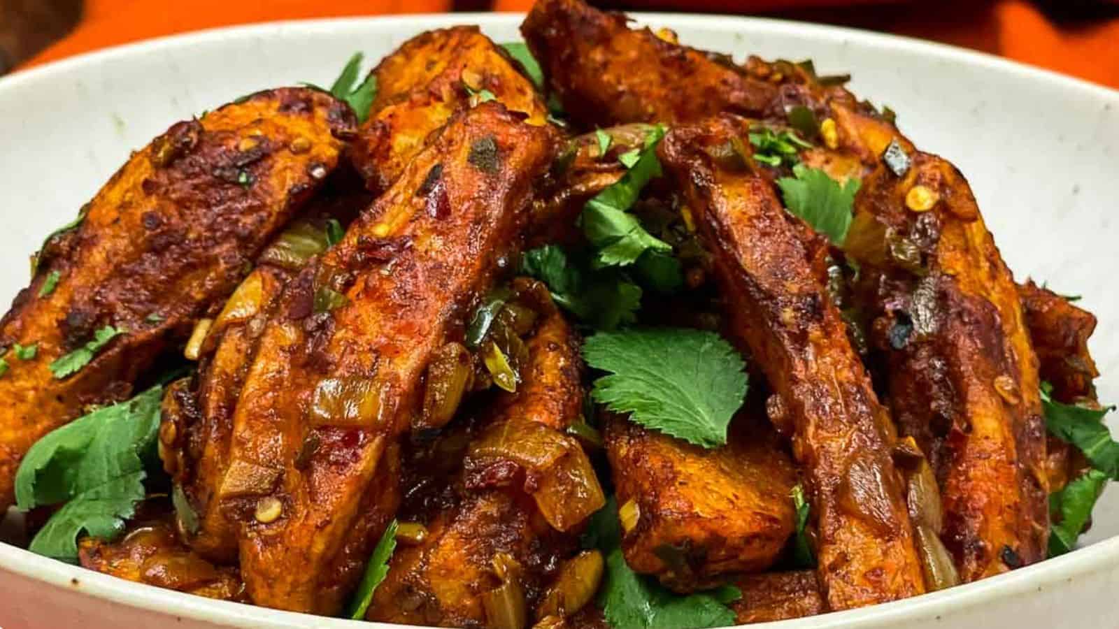 Chili potato recipe served in white bowl with a fork.