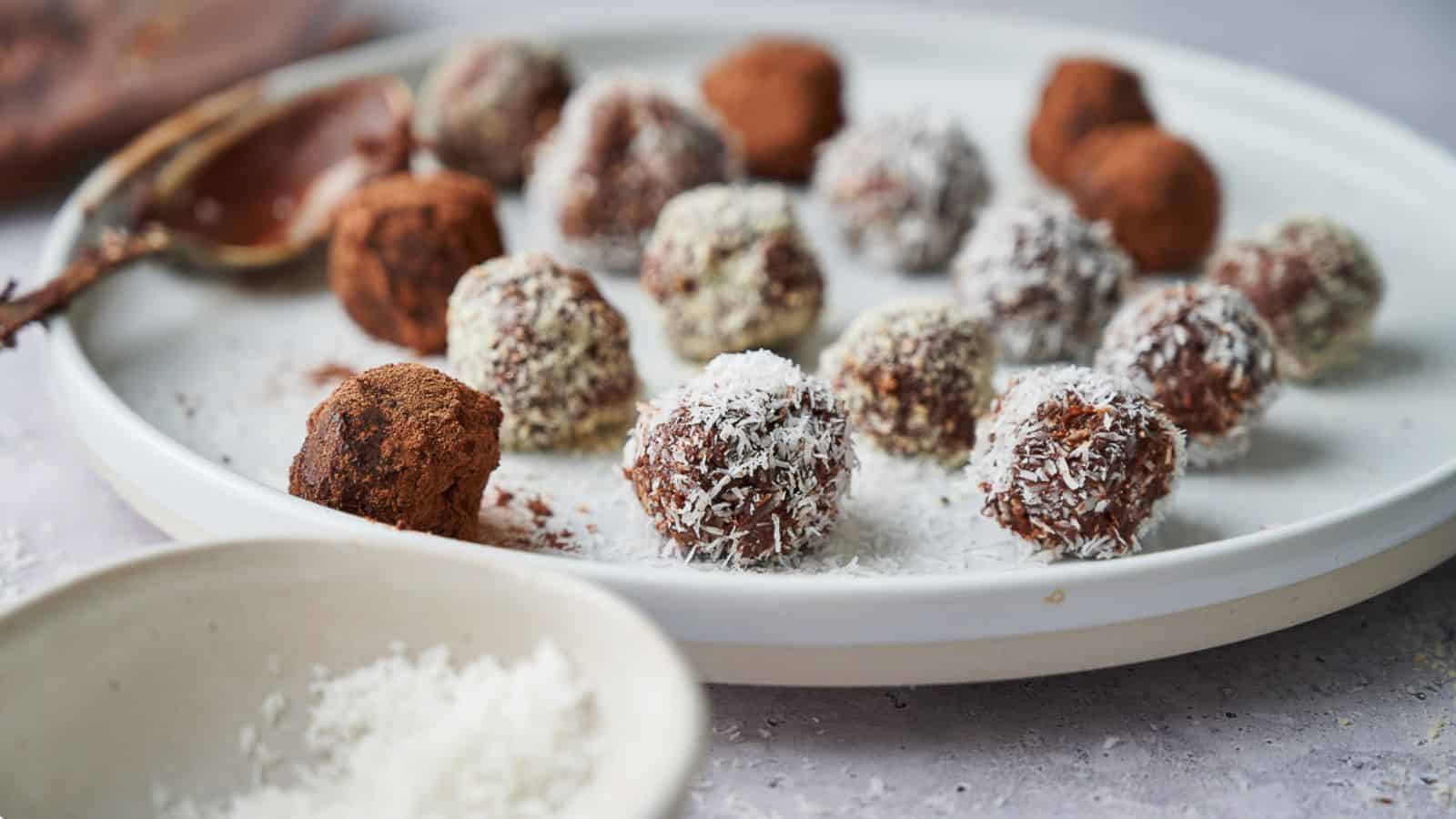 Chocolate truffles on a plate with a chocolatey spoon resting on the plate.