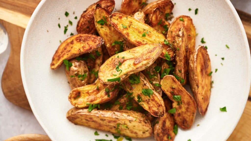 Roasted potato wedges on a white plate.