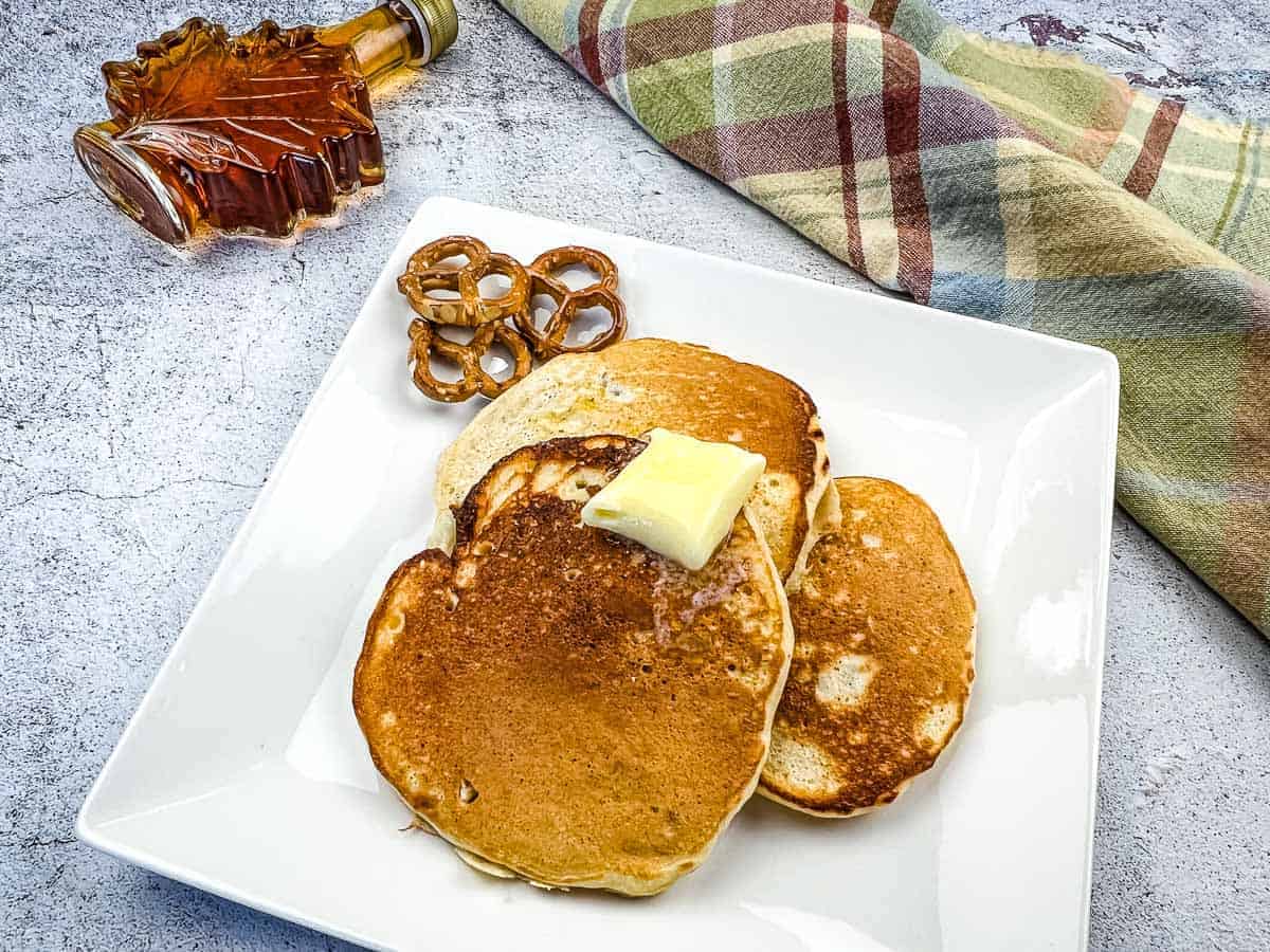 Pretzel pancakes with a bottle of maple syrup nearby.