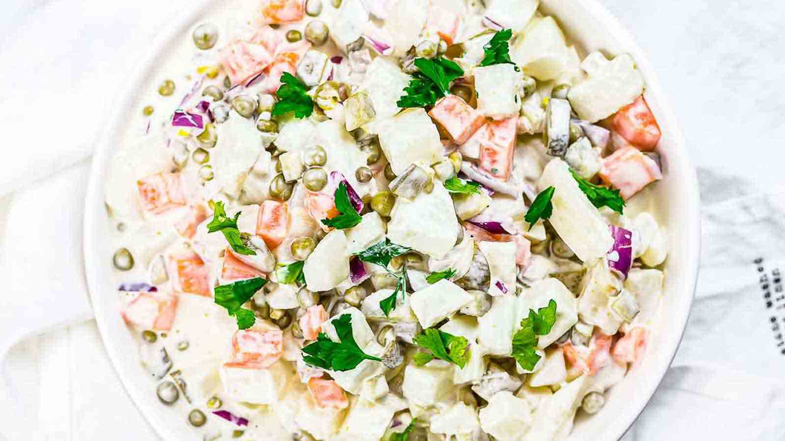 A white bowl of potato salad with mayonnaise. 