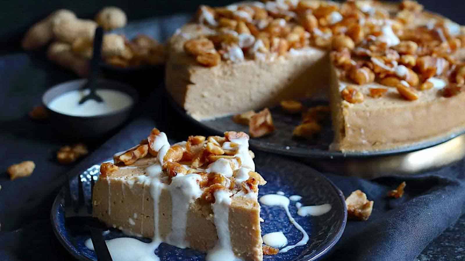 Peanut Butter Cheesecake on a plate with caramelized nuts on top. 