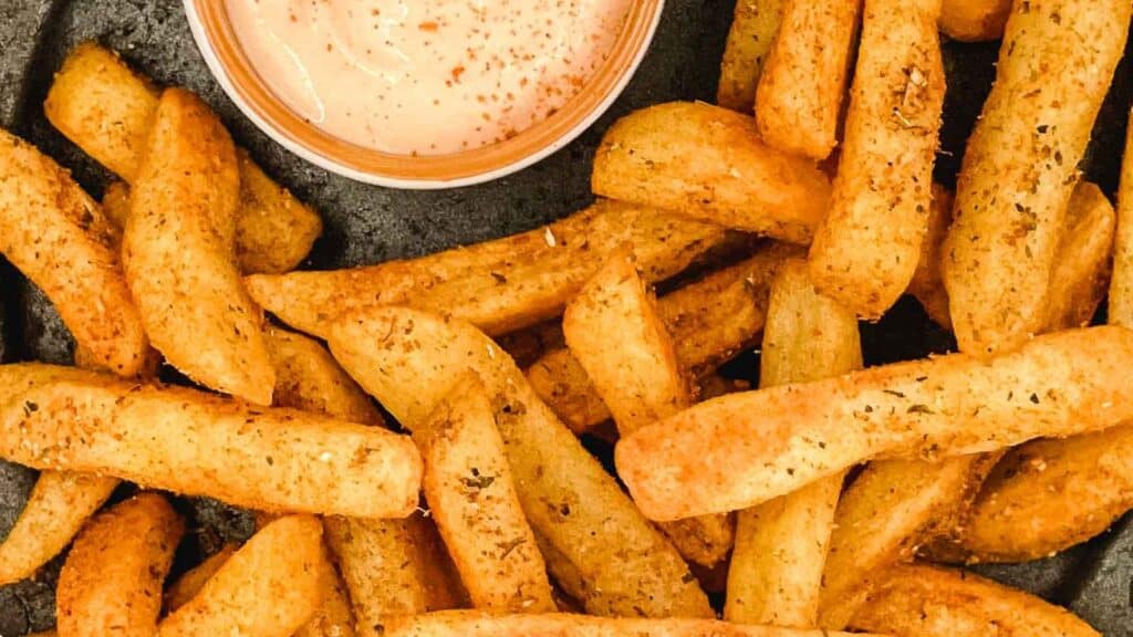 Peri peri fries with dipping sauce on a plate.