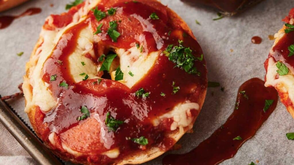 A pizza bagel with bbq sauce and parsley.