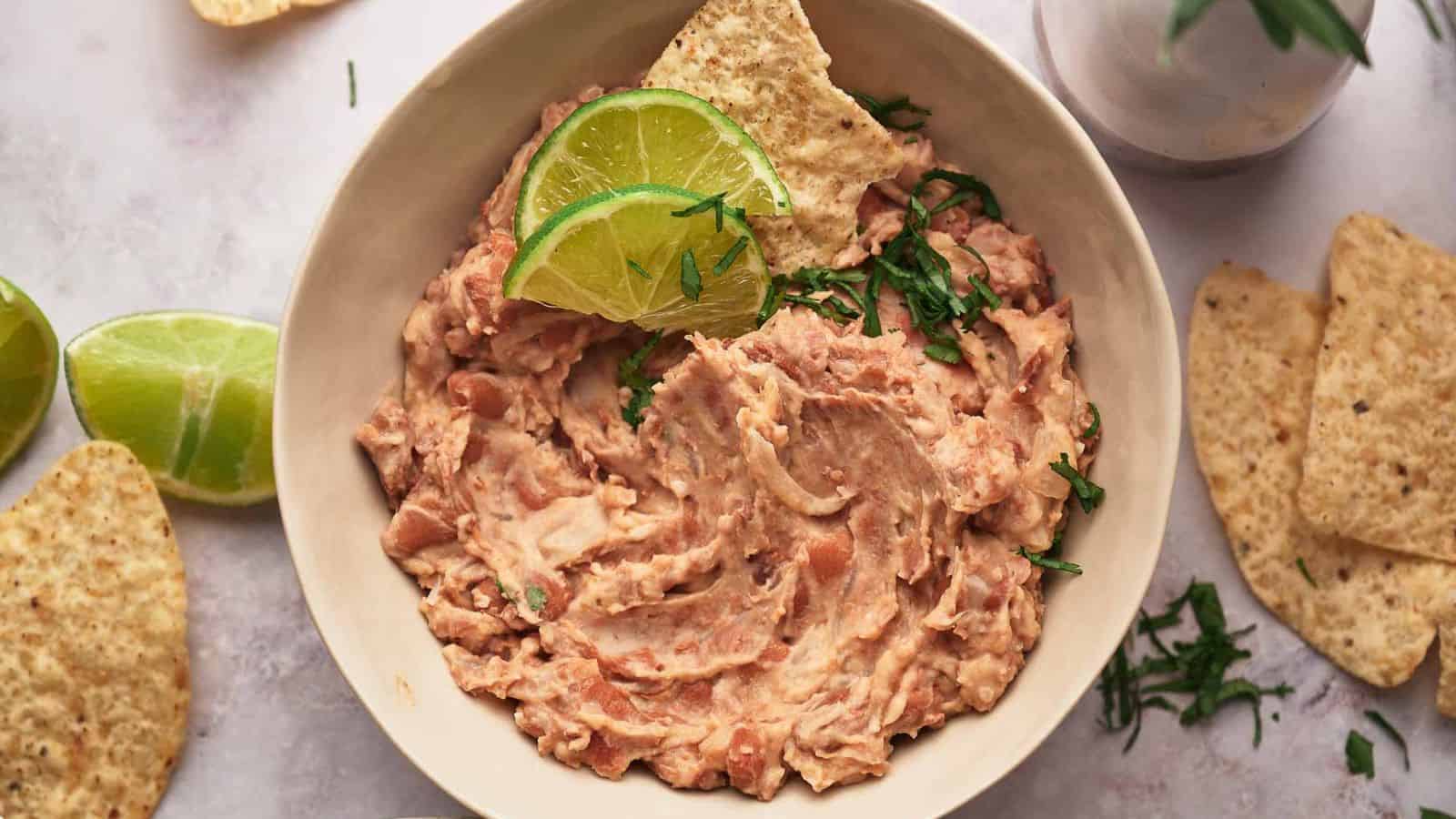 A bowl of homemade refried beans and lime wedges.