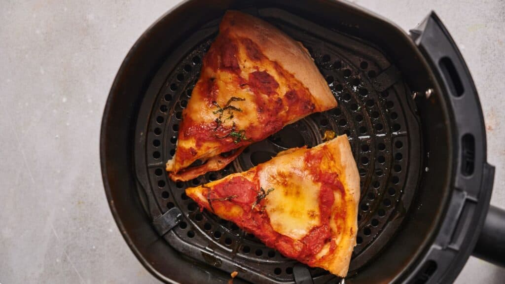 Two slices of pizza in an air fryer.