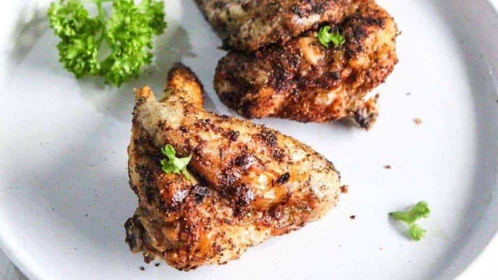 Two chicken breasts on a white plate with parsley.