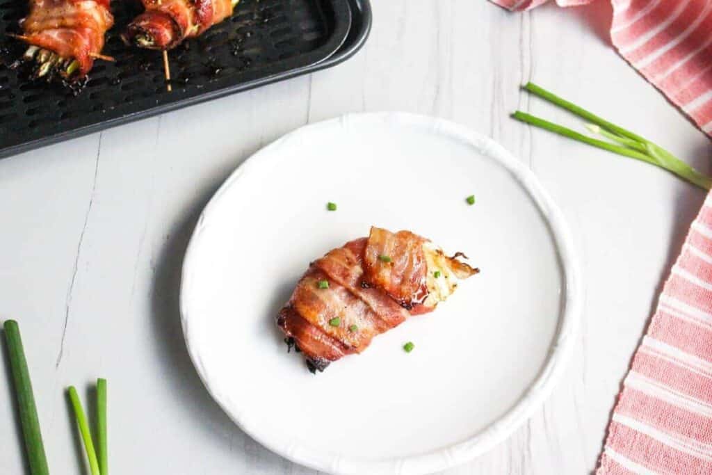 Bacon wrapped asparagus skewers on a white plate.