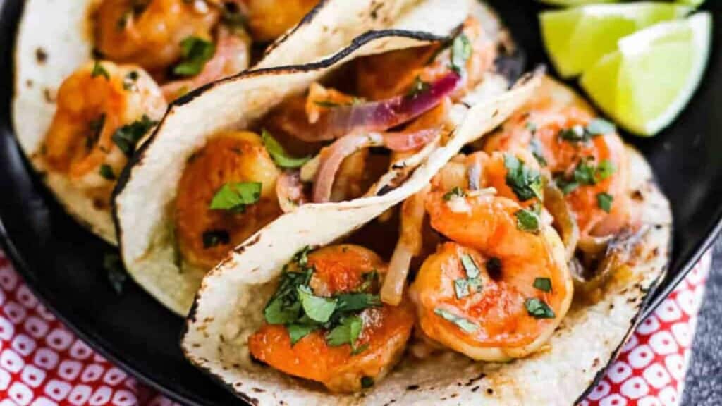 Shrimp tacos on a black plate.