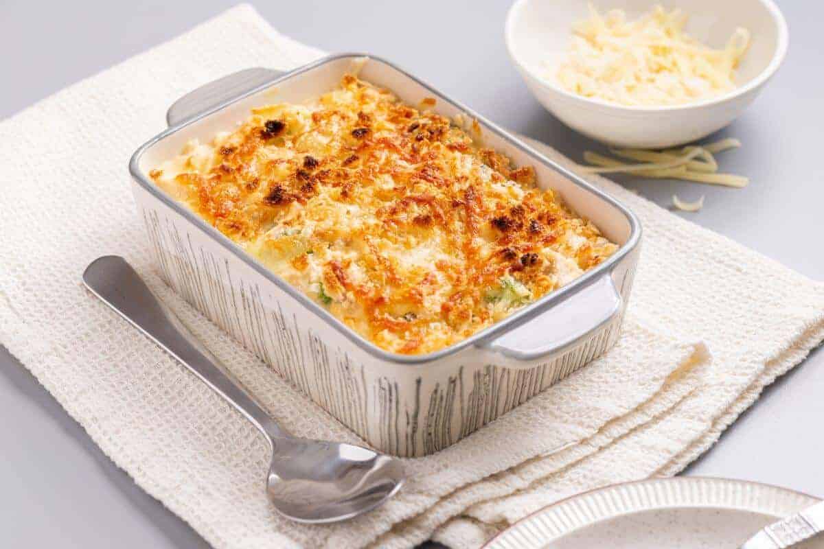 A casserole dish with cheese and broccoli on a napkin.