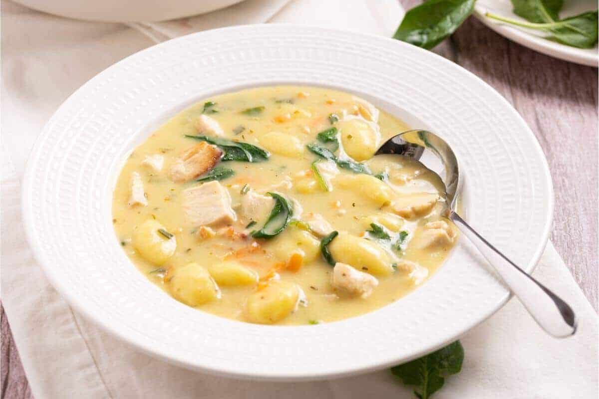 A bowl of chicken and spinach soup with a spoon.