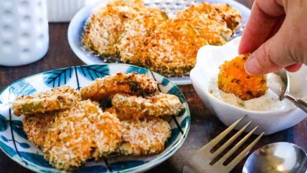 A person dipping a fork into a bowl of fried green tomatoes.