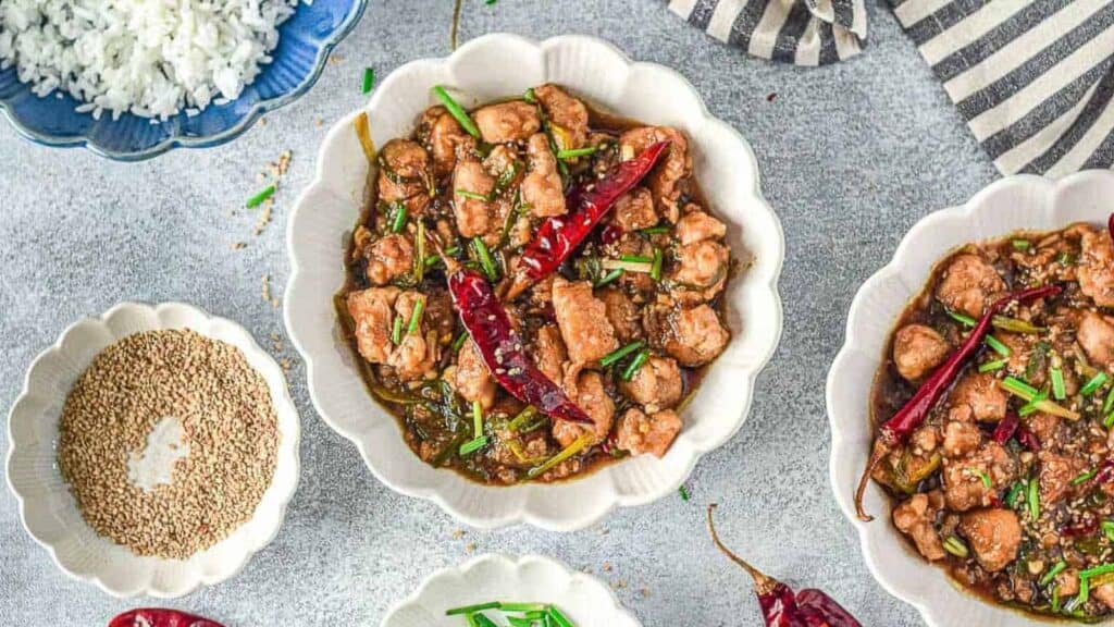 Two bowls of chicken curry with spices and rice.