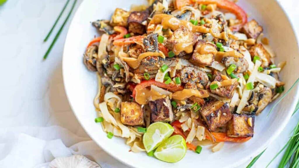 Overhead shot of a bowl of noodles with vegetables and thai peanut sauce.