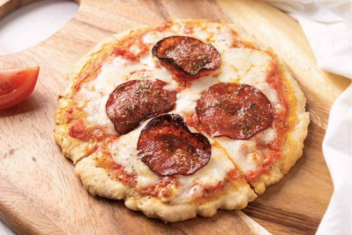 Single serve pepperoni pizza on wooden cutting board.