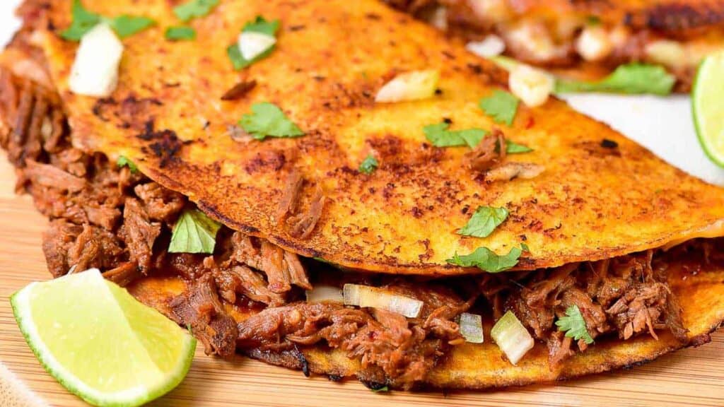 A meat-filled taco on a cutting board with a lime wedge.