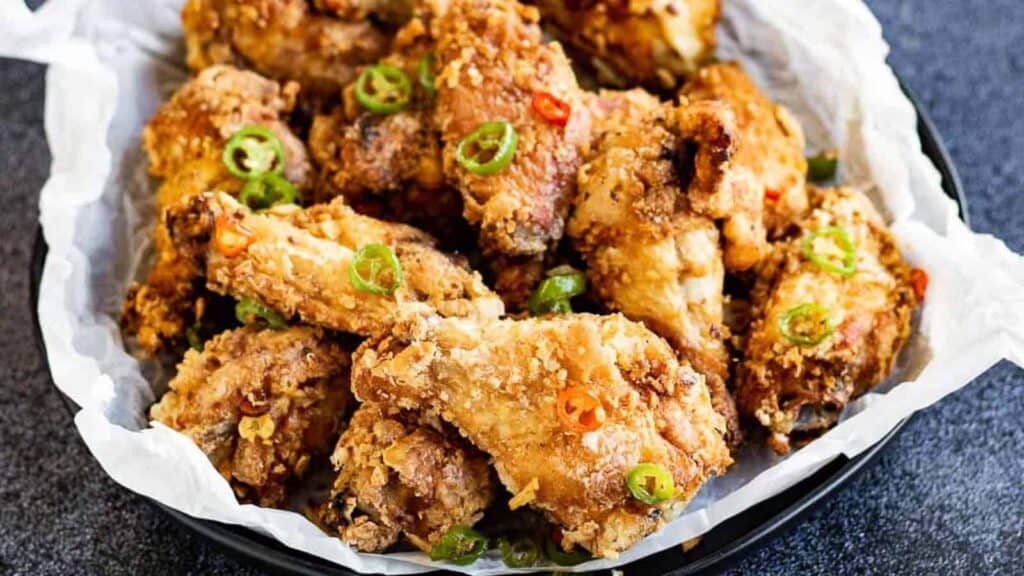 Fried chicken wings in a bowl with chiles.