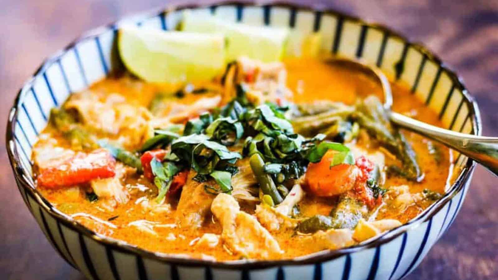 Low angle shot of a blue and white striped bowl filled with Thai chicken curry.