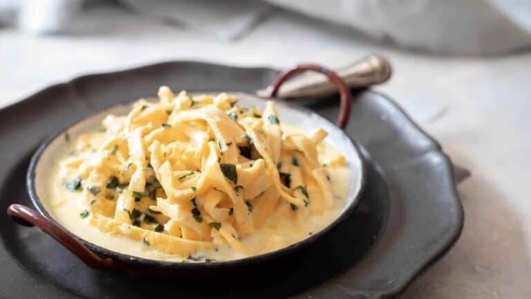 Red plate filled with alfredo sauce and keto noodles.