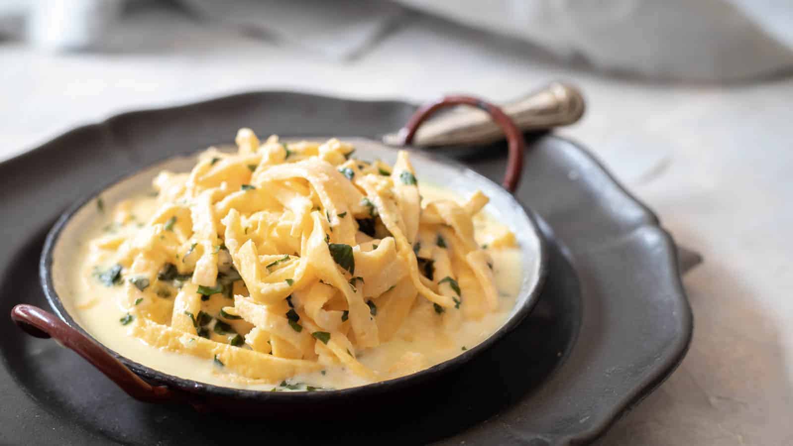 Red plate filled with alfredo sauce and noodles.