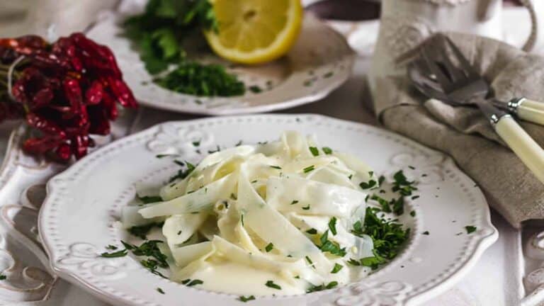 A white plate filled with asparagus pasta and sauce.