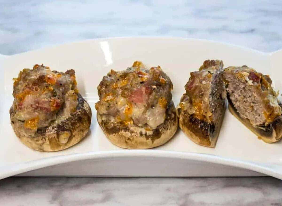 Three stuffed mushrooms on a white plate.