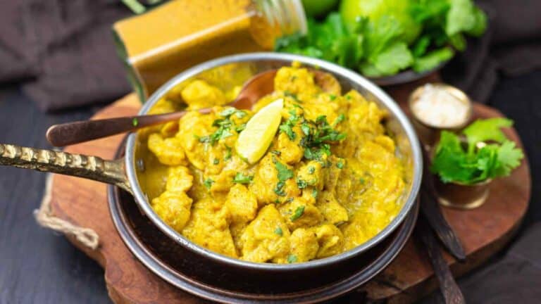 A bowl of chicken curry on a wooden table.