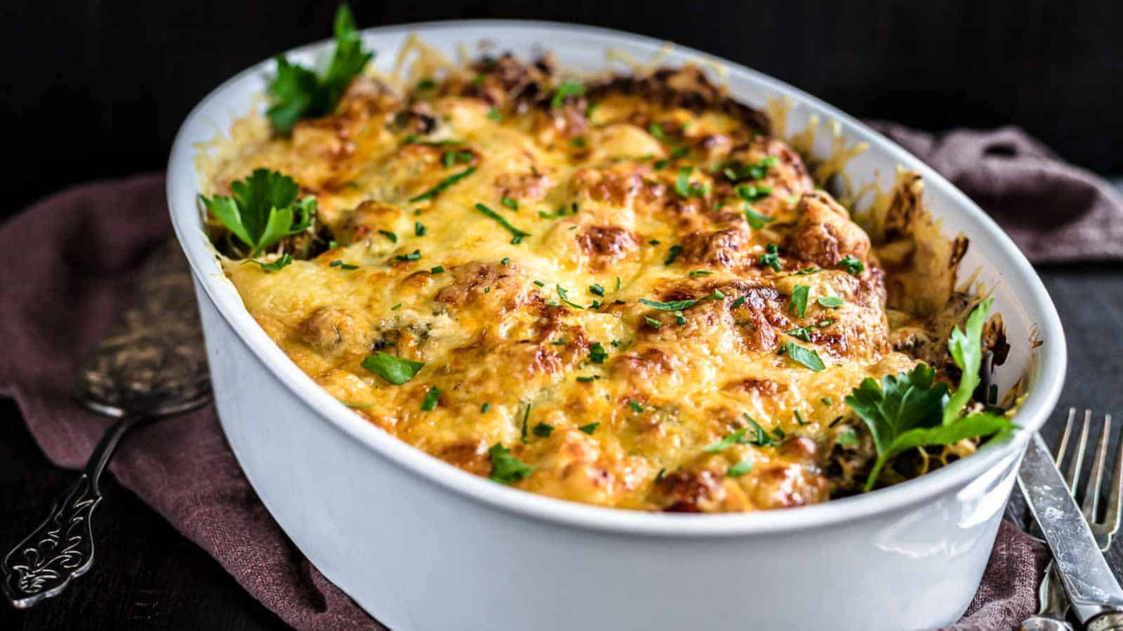 Chicken casserole with baked cheese inside a white dish. 