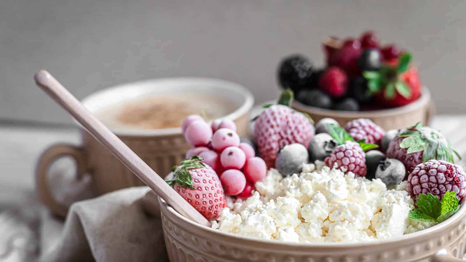 Curd cheese inside a cup with frozen berries. 