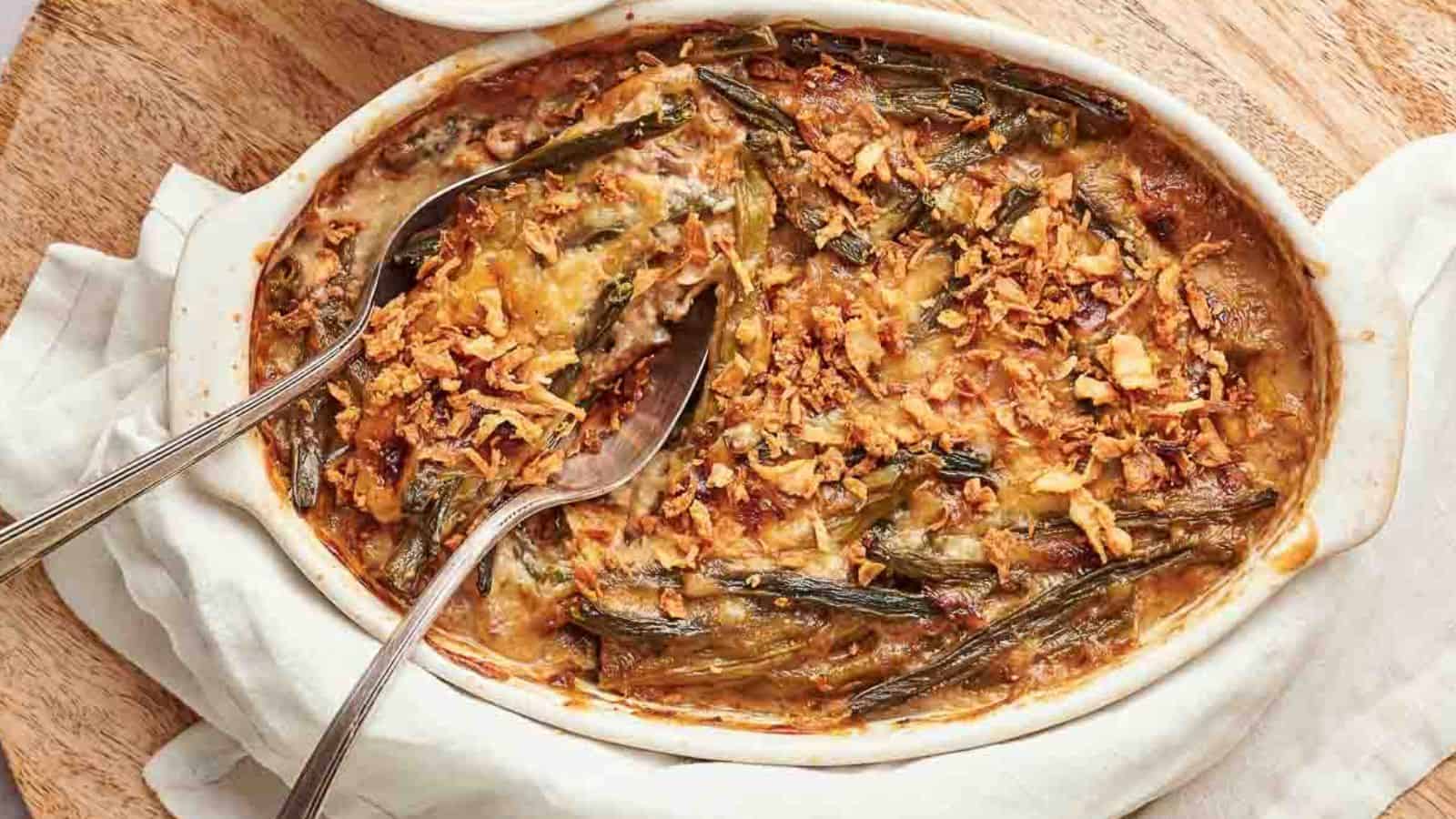 A casserole dish filled with green bean casserole with a spoon in it.