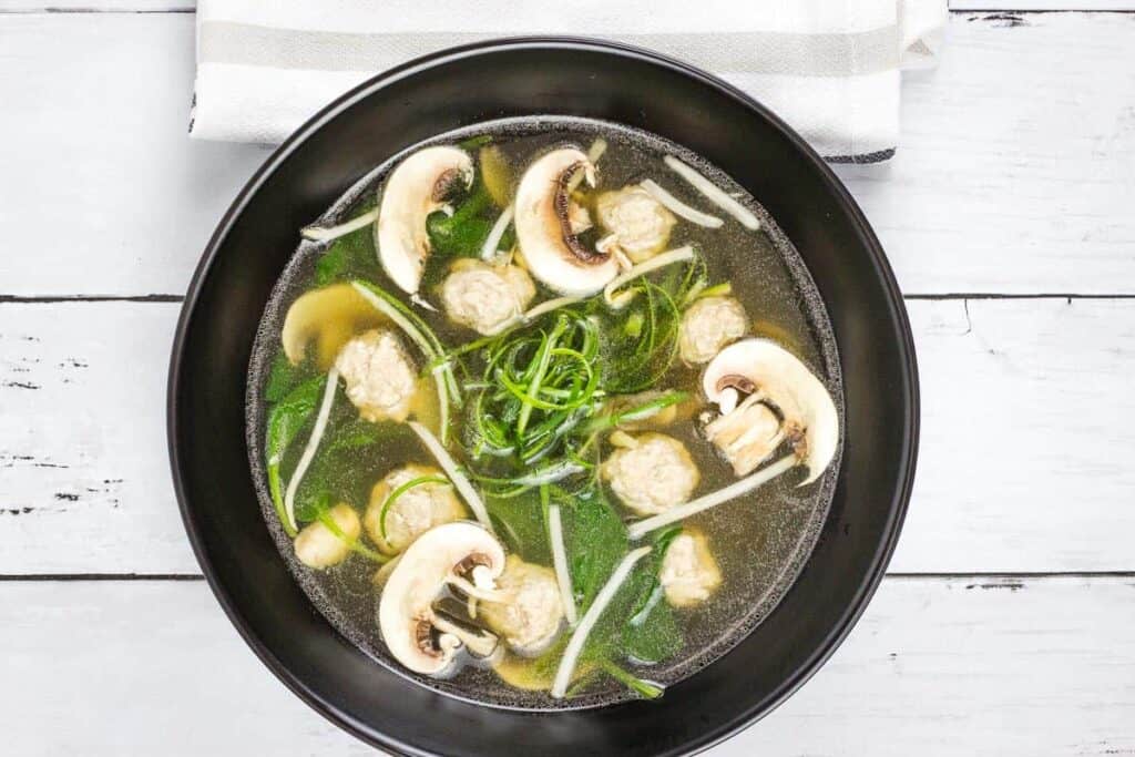 A bowl of Keto Wontonless Soup on a white wooden table.