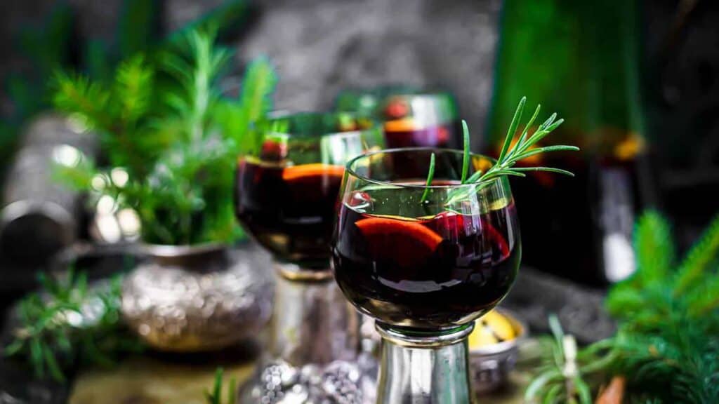 Mulled Wine inside wine glasses with fresh rosemary.