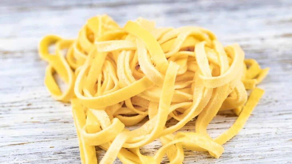 Fettuccini noodles on a wooden board.