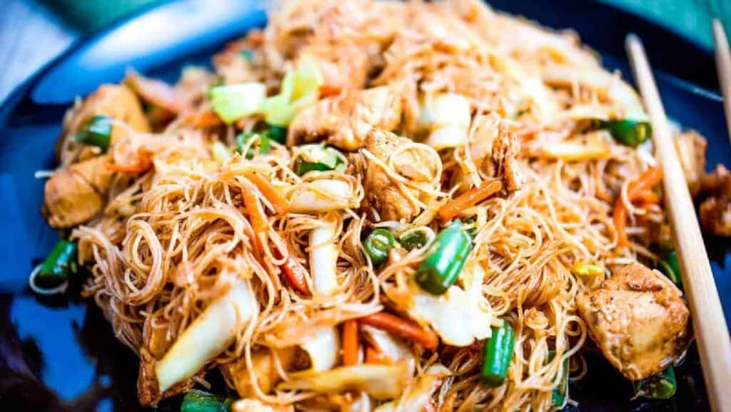 Pancit noodles on a plate with veggies and chicken.