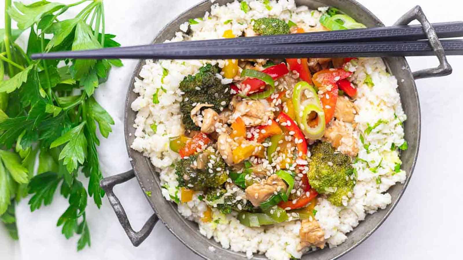 Stir Fry Chicken with cauli rice in a bowl with chopsticks.