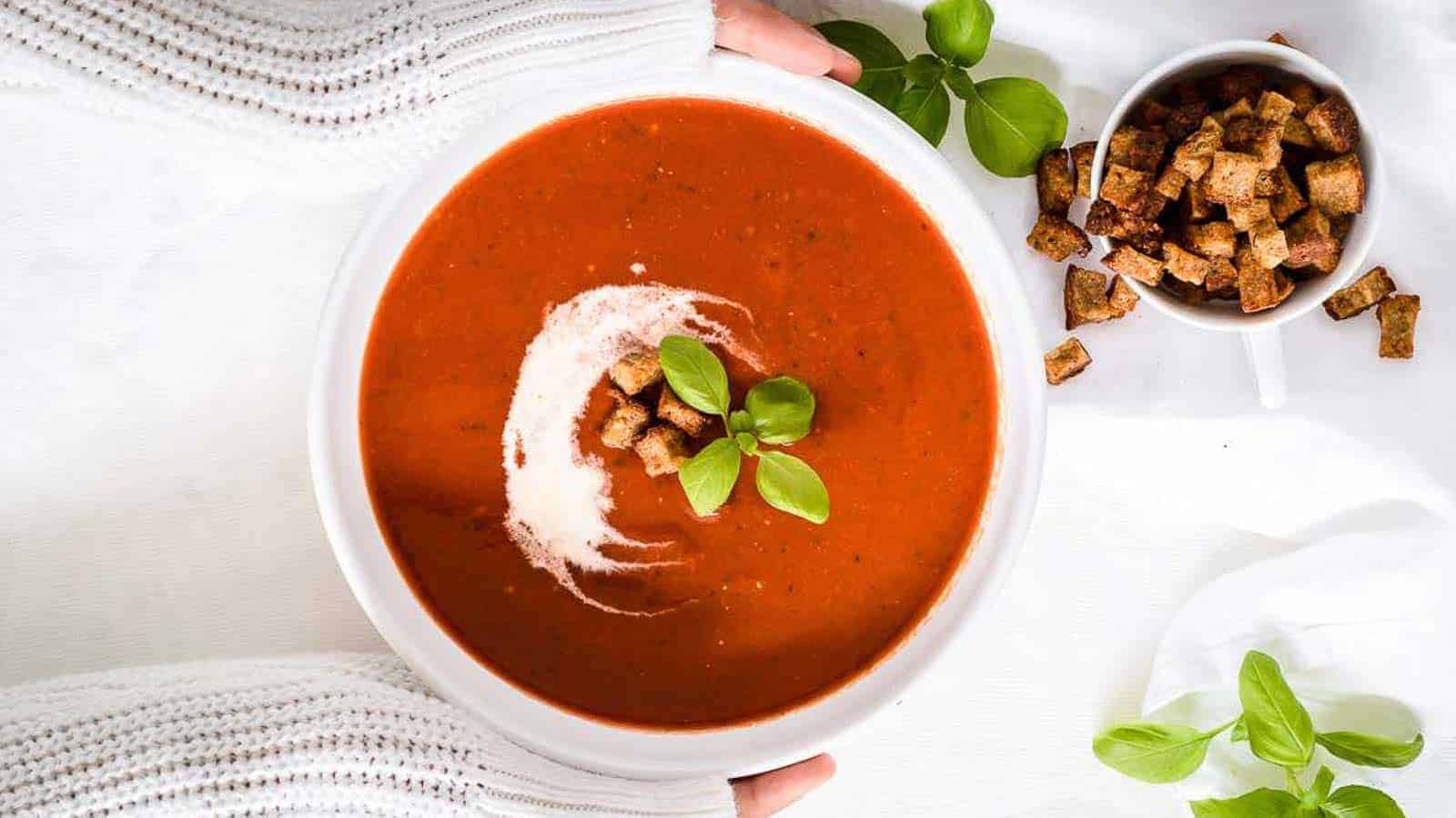 A girl holding a bowl of tomato soup.