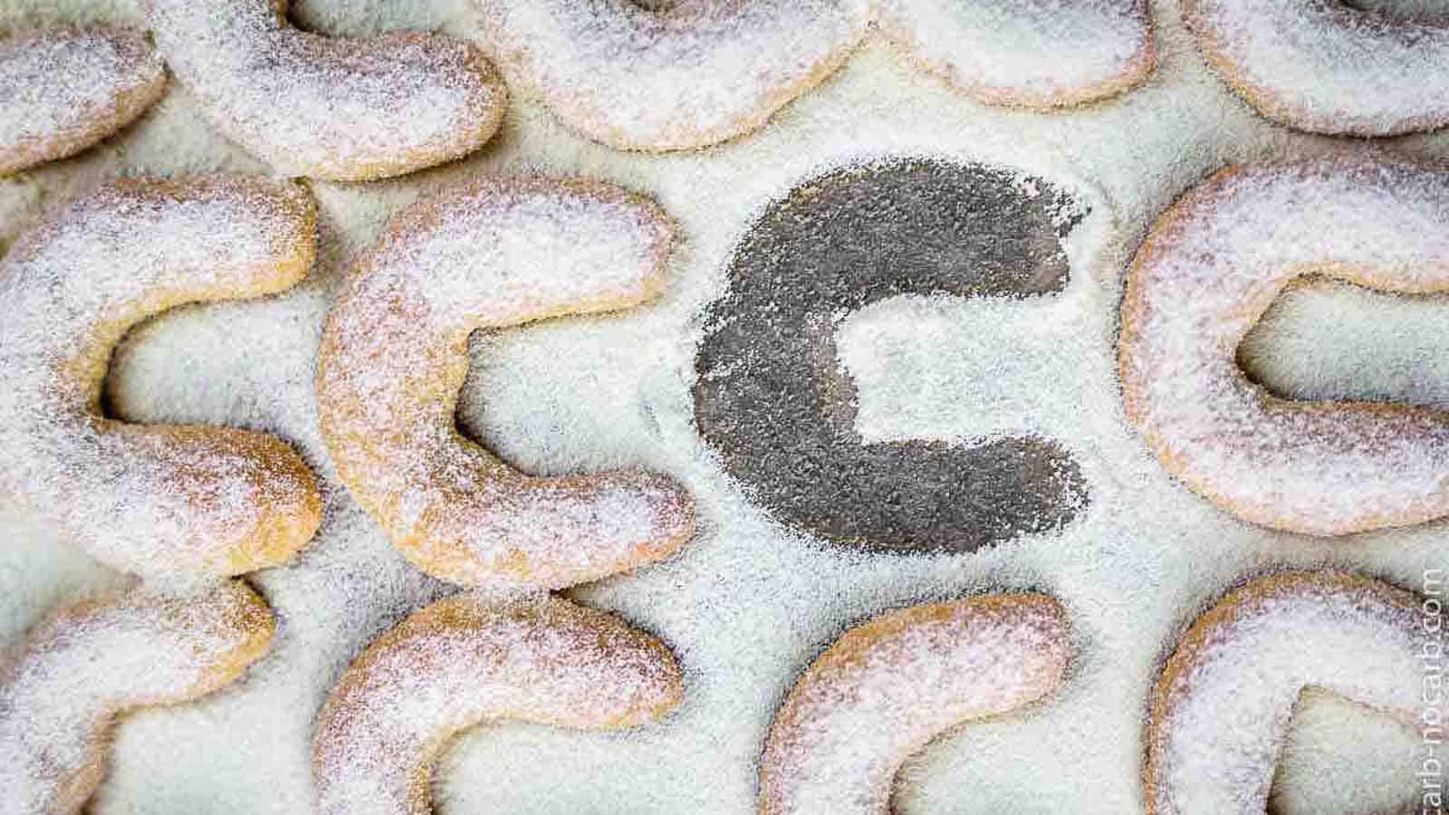 Almond Crescent Cookies on a parchment paper with one piece missing.