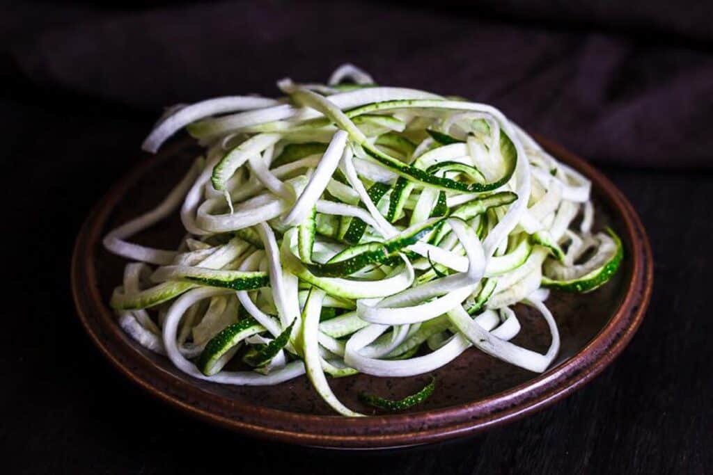 Zucchini noodles in a bowl on a wooden table.