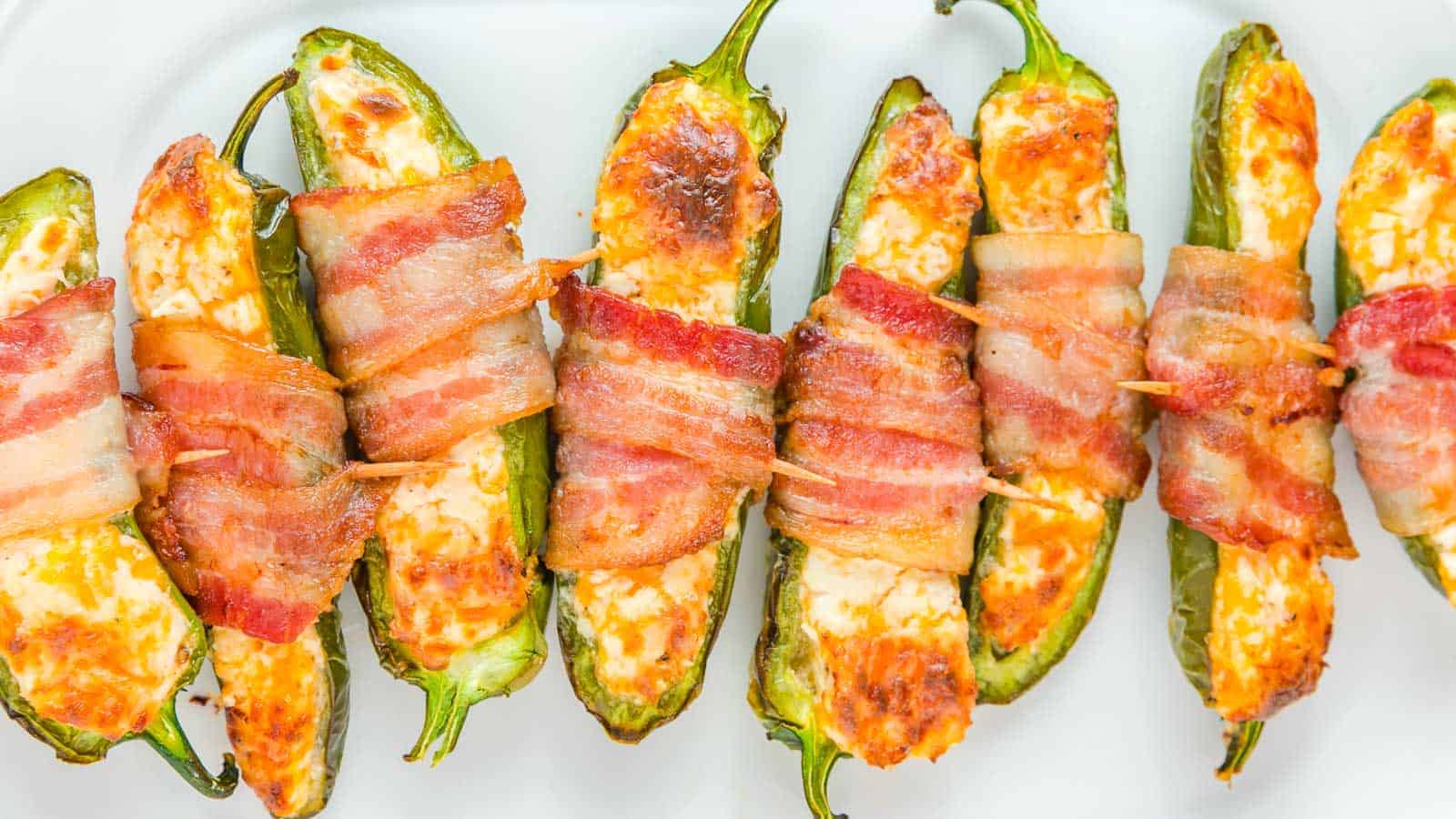 Bacon wrapped jalapenos on a white plate.